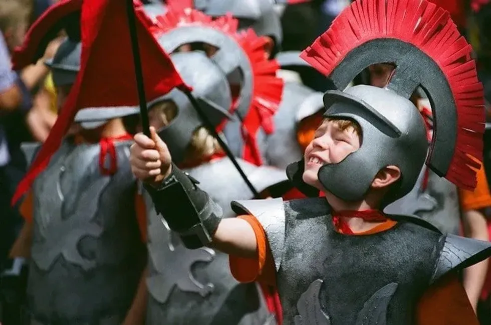 Young boys dressed up as Roman soldiers wearing armour and helmets.