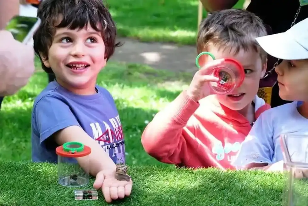 Young boys smiling and laughing while looking at snails.