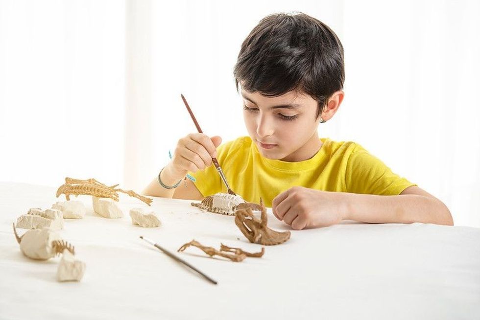 Young child plays as a paleontologist at home.