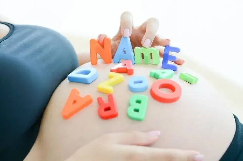 Young expectant mother with letter blocks spelling name on her pregnant belly