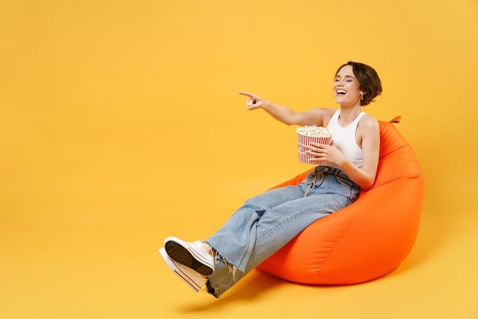 Young friendly woman 20s wear white tank top shirt eat hold takeaway popcorn bucket 