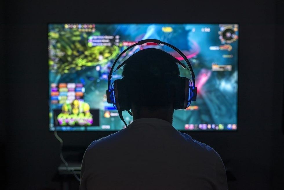 Young gamer playing video game wearing headphone