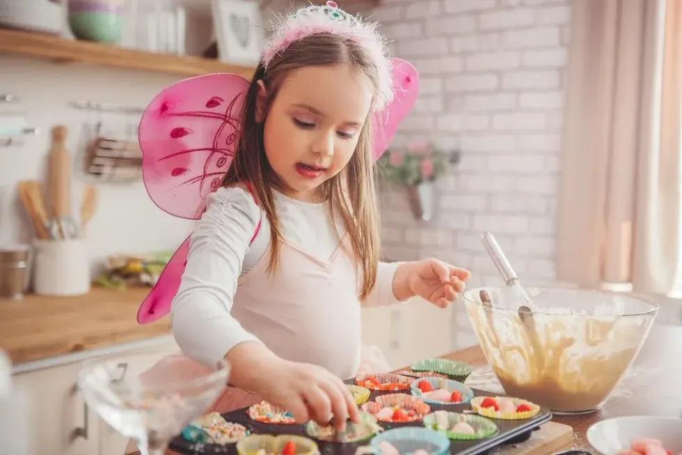 Young girl dressed as a fairy baking rainbow-inspired food.