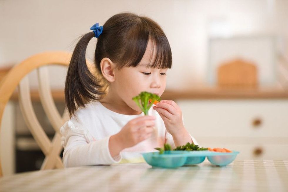 Young girl eating fresh green vegetale.