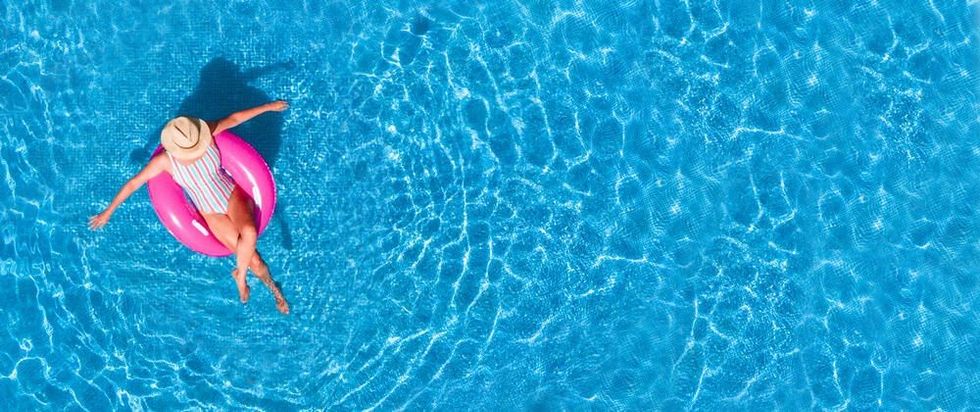 Young girl in a swimsuit and hat floating with pink donut.