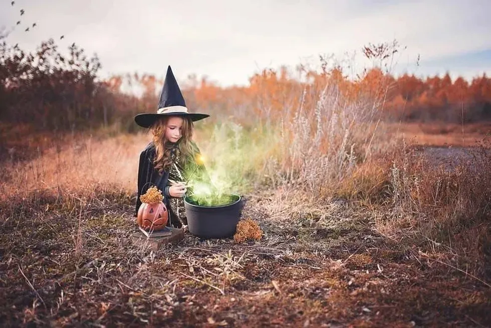 Young girl making a witch potion in a cauldron 