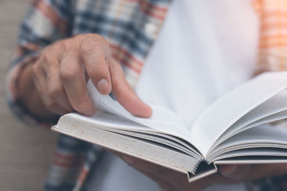 Young man opening and reading a book.