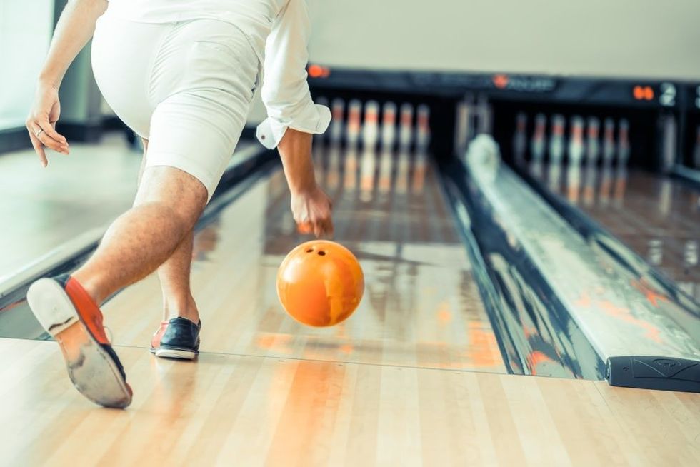 Young man playing bowling at the sport club.