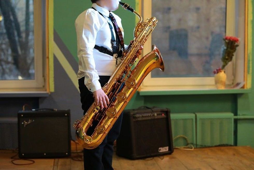Young man student of a music school playing the big golden saxophone