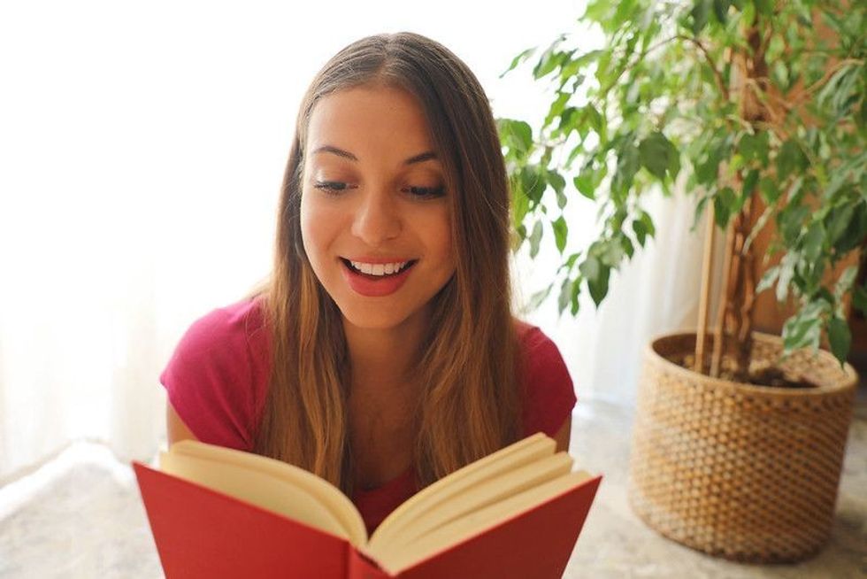 Young pretty woman sitting and reading book.
