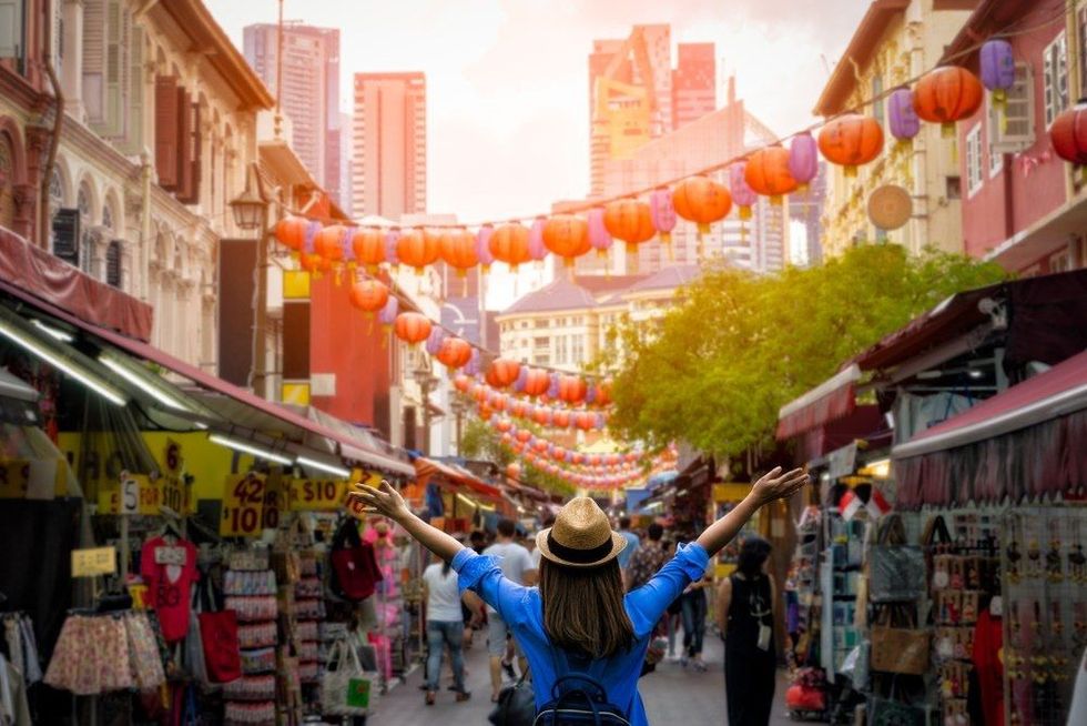 Young woman traveler with backpack and hat traveling into Chinatown at singapore city downtown.