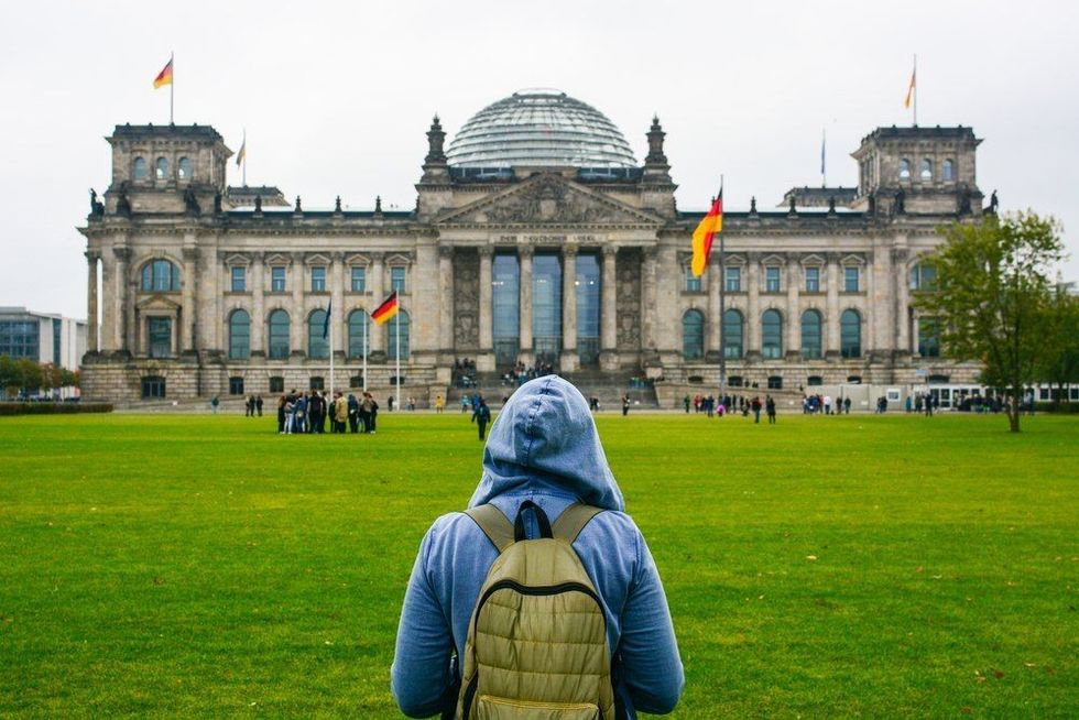 Young woman with backpack looking at Bundestag building in Berlin.