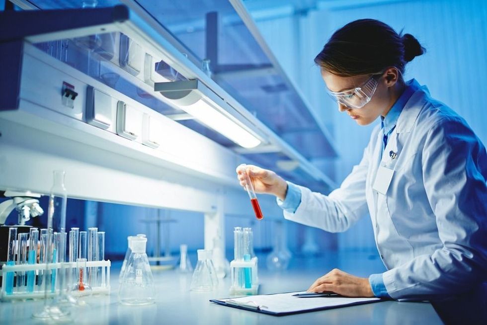 Young woman working with liquids in glassware.